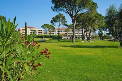 a park with trees and a building in the background at Apartment in Corsica near Palombaggia Beach in Porto-Vecchio