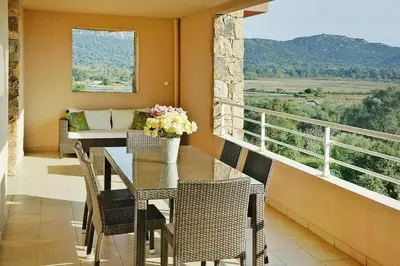 a balcony with a table and chairs and a couch at Apartment in Corsica near Palombaggia Beach in Porto-Vecchio