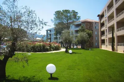 a green yard with a building and a ball in the grass at Residence Salina Bay, Porto Vecchio, Apartment garden side in Porto-Vecchio