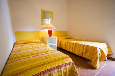 two beds in a hotel room with a mirror at Residence de Tourisme Marina Corsa in Ghisonaccia