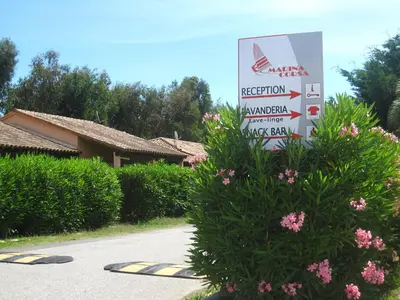 a sign in front of a building with pink flowers at Residence de Tourisme Marina Corsa in Ghisonaccia