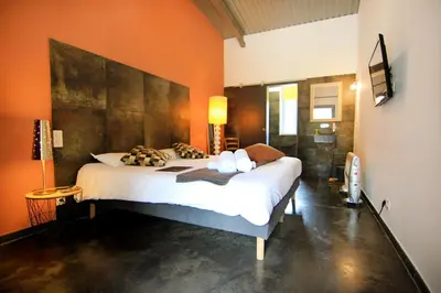 a bedroom with a large bed with orange walls at Hôtel Ascosa Aventure in Ponte-Leccia