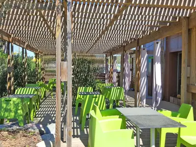 a group of green tables and chairs under a pergola at Hôtel Ascosa Aventure in Ponte-Leccia