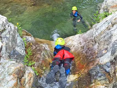 two people are in the water next to a river at Hôtel Ascosa Aventure in Ponte-Leccia