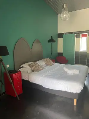 a bedroom with a large bed and a red chair at Hôtel Ascosa Aventure in Ponte-Leccia