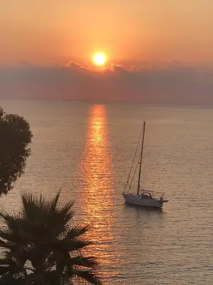 a sail boat in the ocean at sunset at Residence U MELU GRAND T3 JAUNE à l'étage in Tiuccia