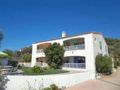 a large white building with a tree in front of it at Residence U MELU GRAND T3 JAUNE à l'étage in Tiuccia