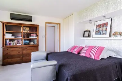 a bedroom with a bed with pink pillows and a chair at Maison 