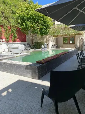 a swimming pool with a table and a chair and an umbrella at Maison 