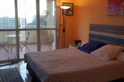a bedroom with a bed and a balcony with a table at dupleix U Forcone in Ajaccio