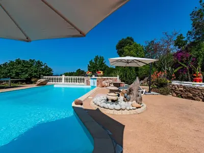 a swimming pool with an umbrella next to a swimming pool at Holiday Home Campestra by Interhome in Coti-Chiavari