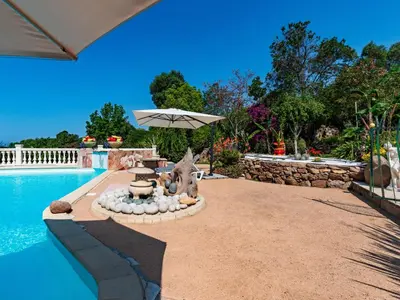 a swimming pool with an umbrella next to a swimming pool at Holiday Home Campestra by Interhome in Coti-Chiavari