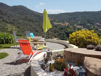 a patio with chairs and a table and a yellow umbrella at Résidence U MELU GRAND T3 ROUGE en rez de jardin in Tiuccia