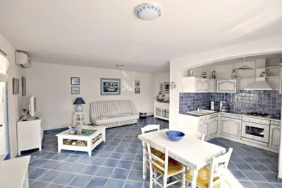 a kitchen and living room with a table and chairs at Résidence U MELU Grand T2 BLEU en rez de jardin in Tiuccia