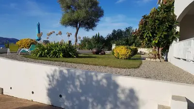 a garden with a white fence and trees and plants at Résidence U MELU Grand T2 BLEU en rez de jardin in Tiuccia