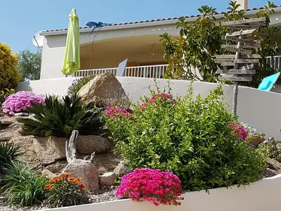 a garden in front of a house with flowers at Résidence U MELU Grand T2 VERT à l'étage in Tiuccia