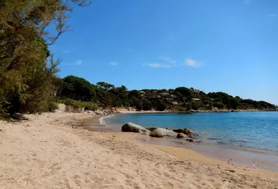 a beach with rocks in the sand and water at Grande Villa, Corse du Sud, Domaine privé de Cala Rossa in Porto-Vecchio