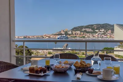 a table with food and a view of the ocean at Residence de Tourisme Ajaccio Amirauté in Ajaccio