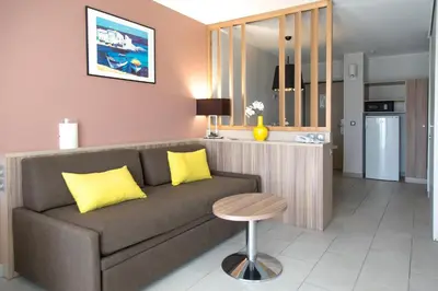 a living room with a couch and a kitchen at Residence de Tourisme Ajaccio Amirauté in Ajaccio