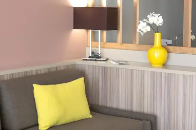 a yellow pillow on a chair in a room at Residence de Tourisme Ajaccio Amirauté in Ajaccio
