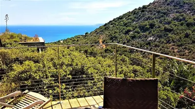 a balcony with two chairs and the ocean in the background at A ALTEZZA Palombaggia in Porto-Vecchio