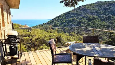 a table and chairs on a deck with a view of a mountain at A ALTEZZA Palombaggia in Porto-Vecchio