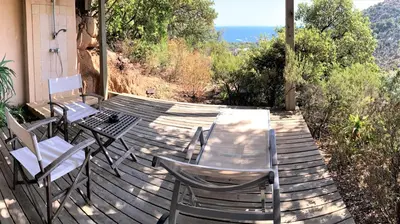 a wooden deck with chairs and a table on it at A ALTEZZA Palombaggia in Porto-Vecchio