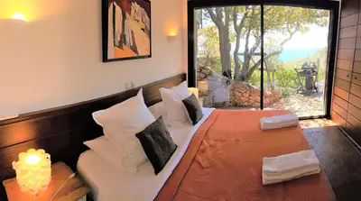 a bedroom with a bed with pillows and a window at A ALTEZZA Palombaggia in Porto-Vecchio