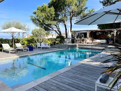 a swimming pool with chairs and an umbrella at Les Suites d'Agosta in Porticcio