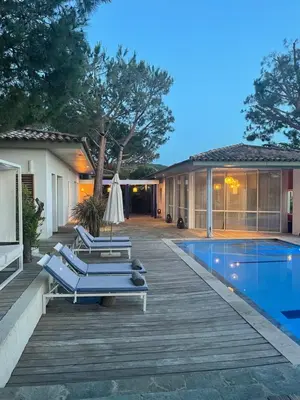 a house with a wooden deck and a swimming pool at Les Suites d'Agosta in Porticcio