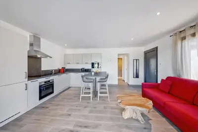 a living room with a red couch and a kitchen at Résidence Pierre & Vacances Premium Les Terrasses d'Arsella in Porto-Vecchio