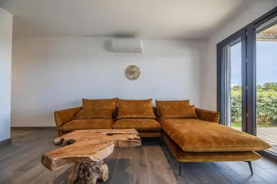 a living room with a brown couch and a wooden table at Résidence Pierre & Vacances Premium Les Terrasses d'Arsella in Porto-Vecchio