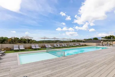 a pool with chairs and umbrellas at a resort at Résidence Pierre & Vacances Premium Les Terrasses d'Arsella in Porto-Vecchio