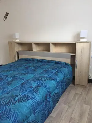 a bed with a blue comforter in a room at Bottega in Petreto-Bicchisano
