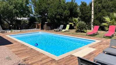 a swimming pool in a yard with two chairs and a table at Bottega in Petreto-Bicchisano