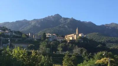 a town on a hill with mountains in the background at Bottega in Petreto-Bicchisano