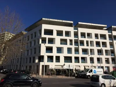 a white building with cars parked in front of it at Studio les pieds dans l'eau Plage du Trottel in Ajaccio