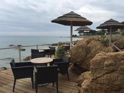 a wooden deck with tables and umbrellas on the beach at Barbicaja in Ajaccio
