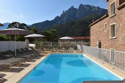 a swimming pool with chairs and umbrellas next to a building at Résidence Idéal-Subrini in Porto Ota