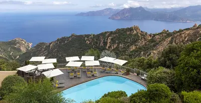 a swimming pool with chairs and a view of the ocean at Hôtel Capo Rosso in Piana