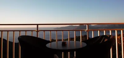 a table on a balcony with a view of the mountains at Hôtel Capo Rosso in Piana