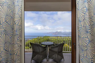 a balcony with a table and a view of the ocean at Hôtel Capo Rosso in Piana