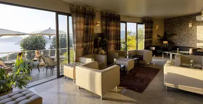 a restaurant with couches and tables and a balcony at Hôtel Capo Rosso in Piana