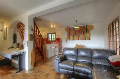 a living room with a leather couch and a kitchen at La Baraka in Pianottoli-Caldarello