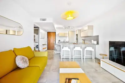 a living room with a yellow couch and a kitchen at Domaine du Frassu, T2 standing, plage à pied in Porticcio