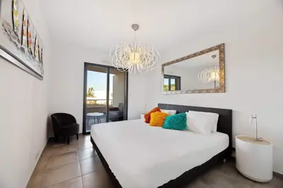 a bedroom with a bed with a mirror and a chandelier at Domaine du Frassu, T2 standing, plage à pied in Porticcio