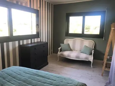 a bedroom with a bed and a chair and two windows at Oliera 2 in Oletta