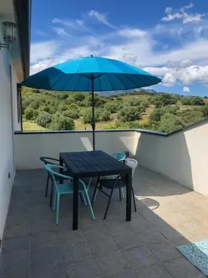 a table and chairs with a blue umbrella on a balcony at Oliera 2 in Oletta