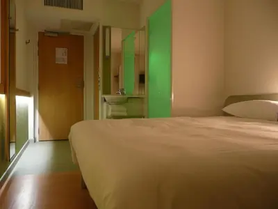 a bedroom with a bed and a bathroom with a sink at ibis budget Ajaccio in Ajaccio
