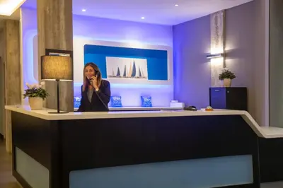 a woman talking on a cell phone at a reception desk at ibis budget Ajaccio in Ajaccio